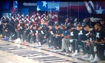 Jugadores, entrenadores y árbitros se arrodillan durante el himno